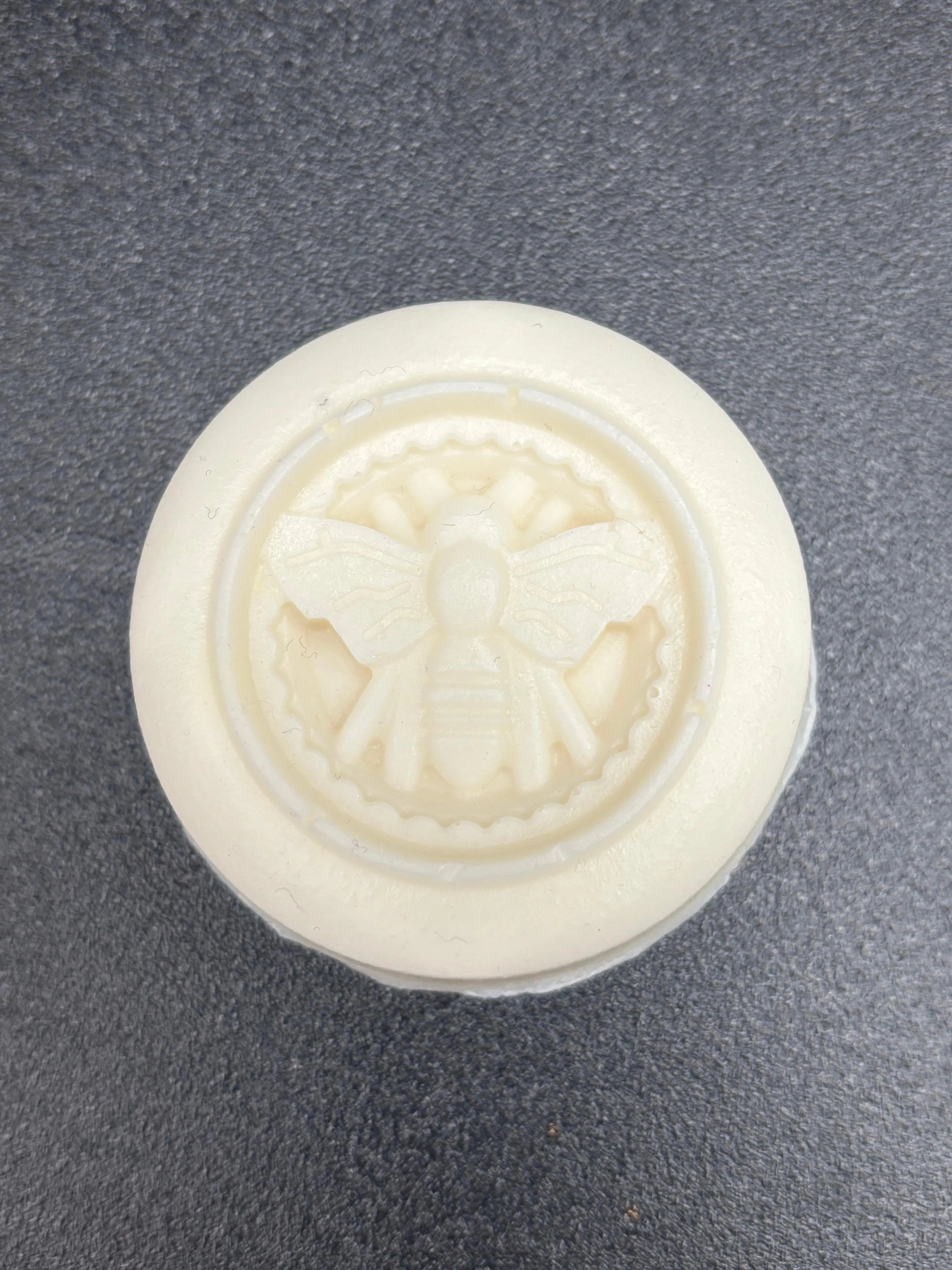 White soap with a bee design on a gray background