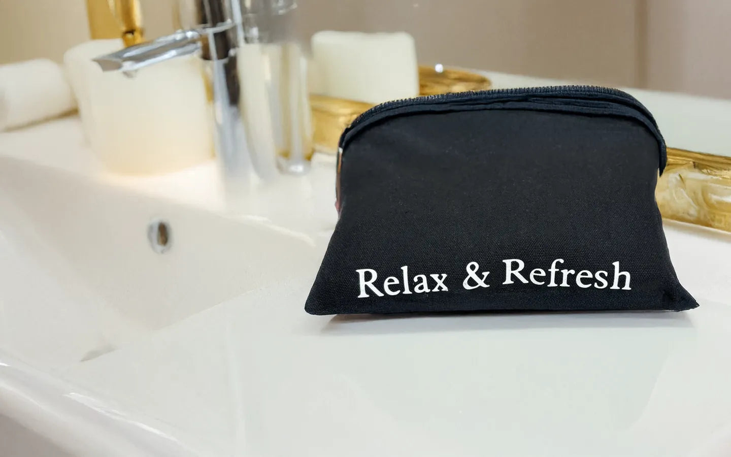 Black pouch with 'Relax & Refresh' text on a bathroom counter